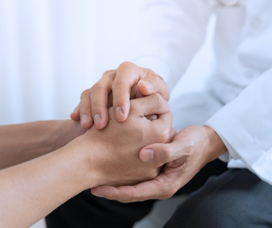 PCA NWA mental health services - Close-up of a person in a white coat gently holding another's hands, suggesting comfort or support in a clinical setting, as often seen during EMDR Therapy sessions.