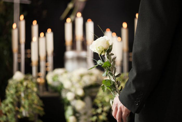 person at a funeral holding a white flower