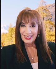 PCA NWA mental health services - Kathryn Malbica, LCSW smiles in front of a scenic background with autumn trees and mountains.