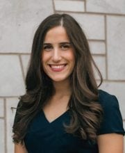 PCA NWA mental health services - Haley Medford, LMSW stands in front of a light-colored stone wall, smiling at the camera, radiating warmth and a passion for psychology.